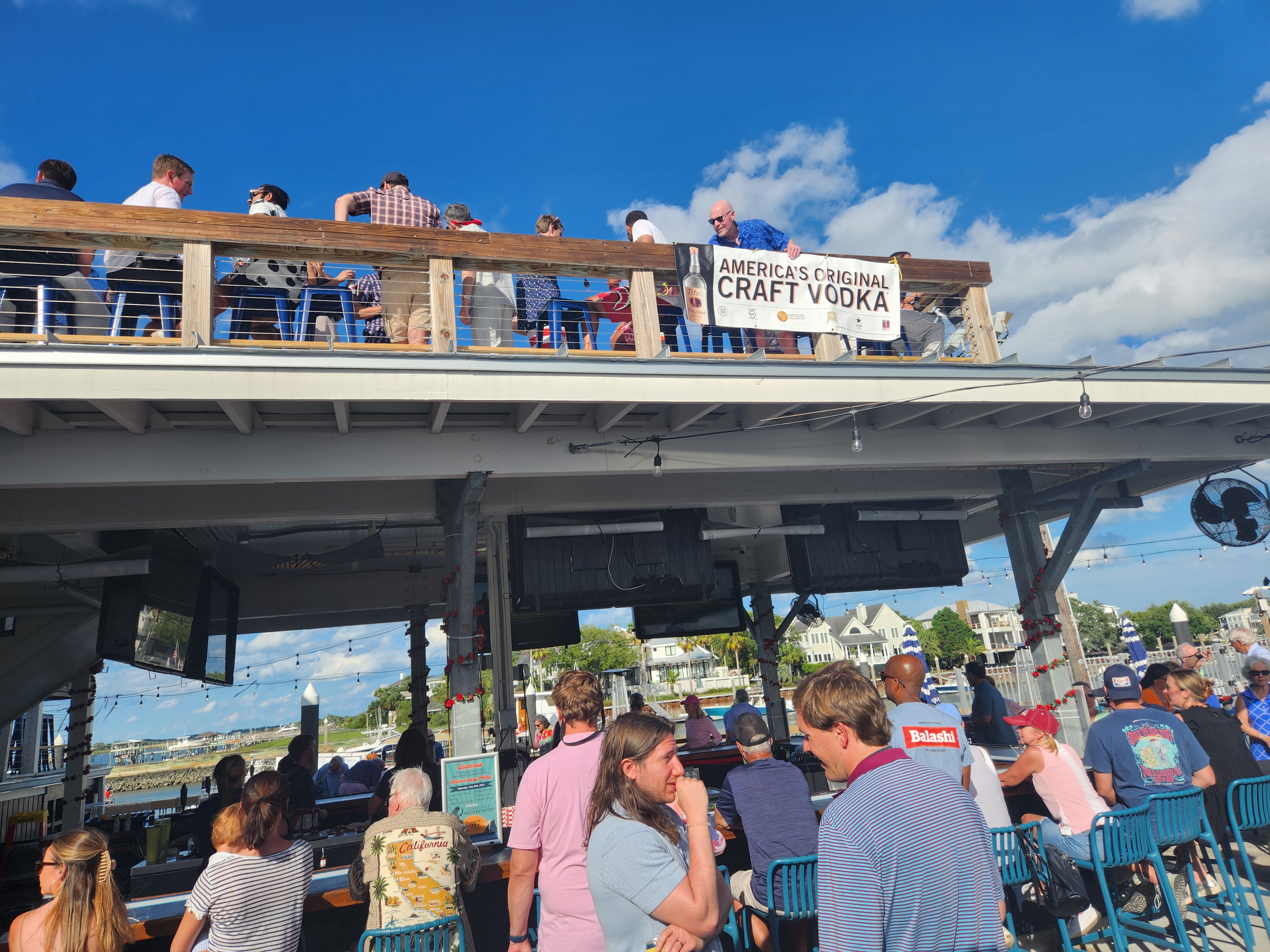 Wild Dunes members at Shem Creek waterfront bar with America's Original Craft Vodka banner
